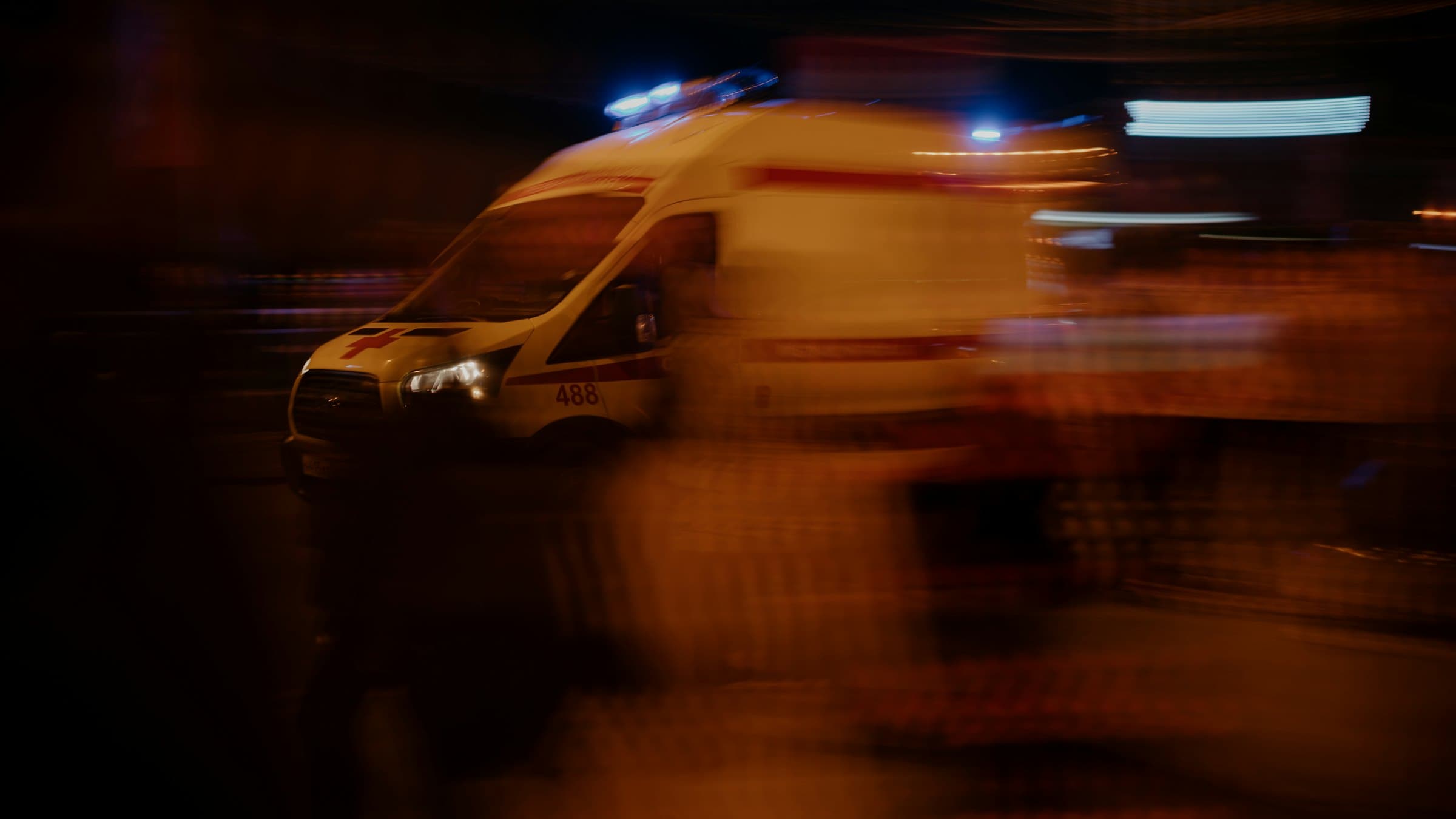 An ambulance moving at speed through the city at night